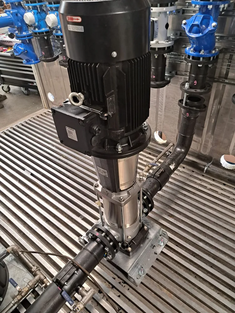 Vertical multistage booster pump on the floor of the pump container